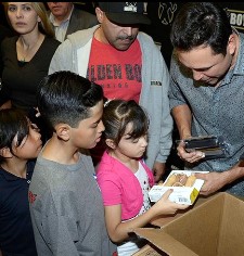 Happy with the children, Oscar gives boxng equipment and explains the gifts as he hands them out.